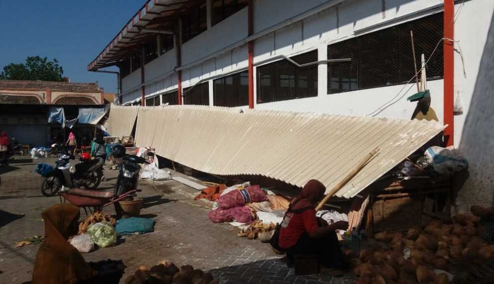 Pedagang beraktifitas di dekat atap yang ambruk