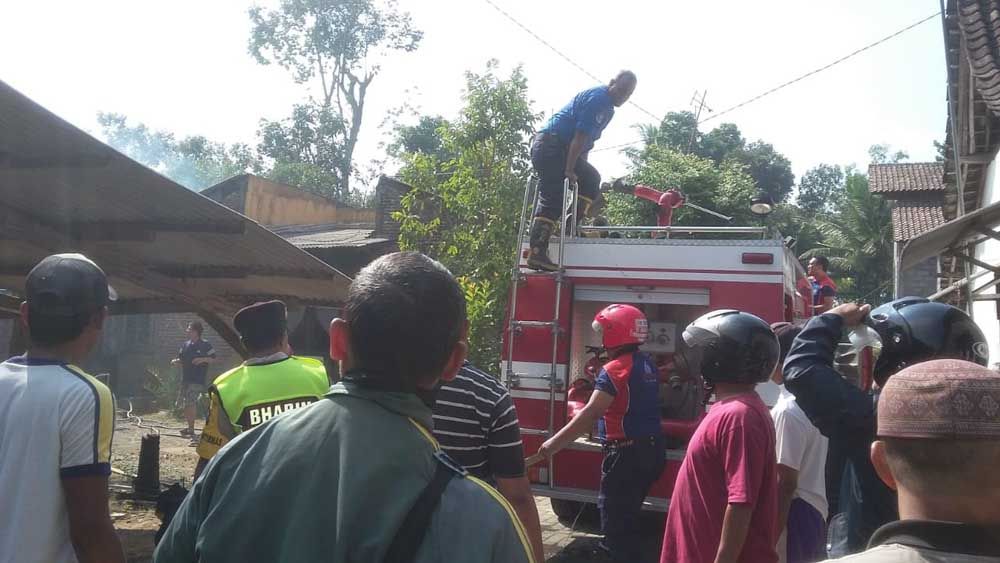 Petugas PMK dan warga berupaya memadamkan api yang membakar rumah Mbah Nur