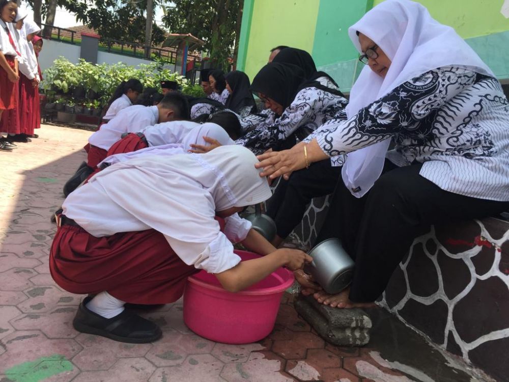 Siswa membasuh kaki para guru