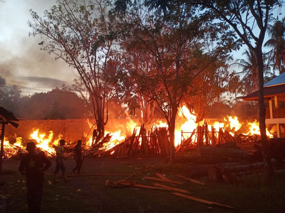 Warga membantu memadamkan api yang membakar gudang kayu dan meubel di Banyuwangi yang terbakar