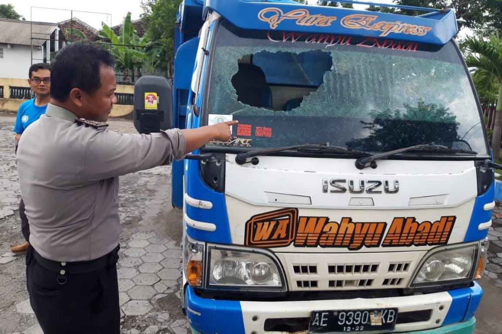 Polisi menunjukkan truk korban yang rusak kacanya akibat dilempar pelaku dengan batu
