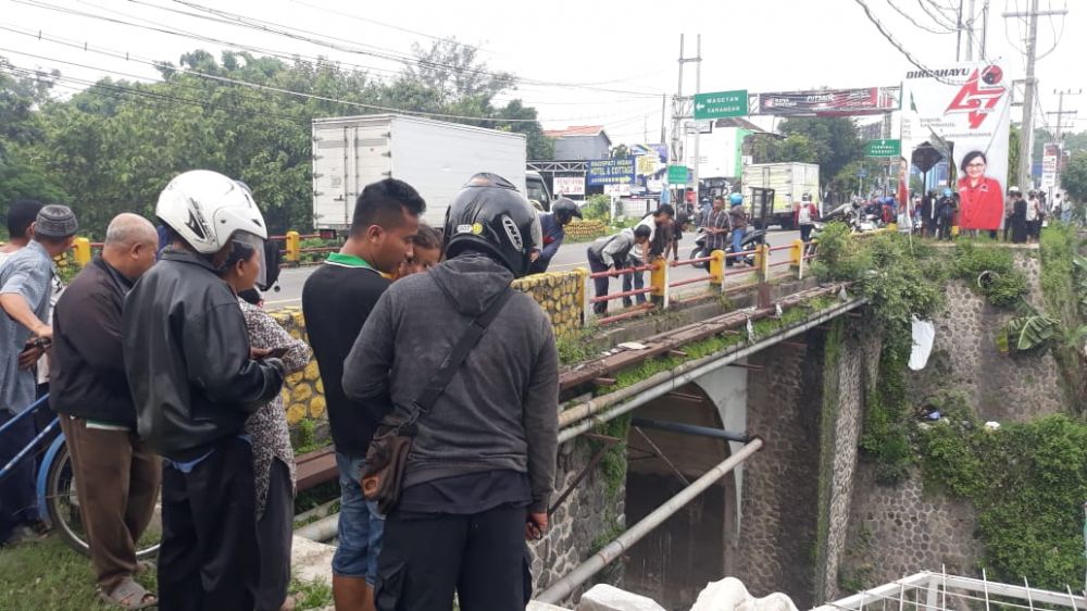 Warga menyaksikan proses evakuasi kedua korban yang terjun ke sungai di Magetan
