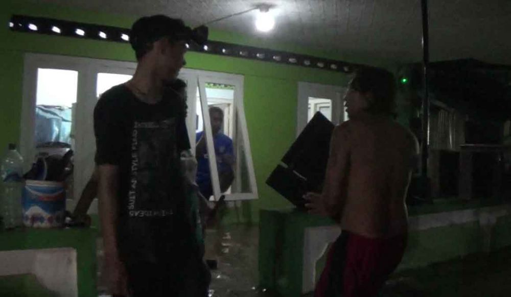 Warga mengangkat barang saat banjir datang