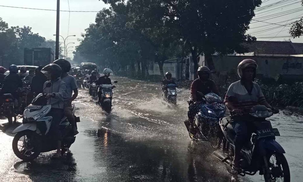 Pengendara motor melaju di tengah jalan hindari banjir