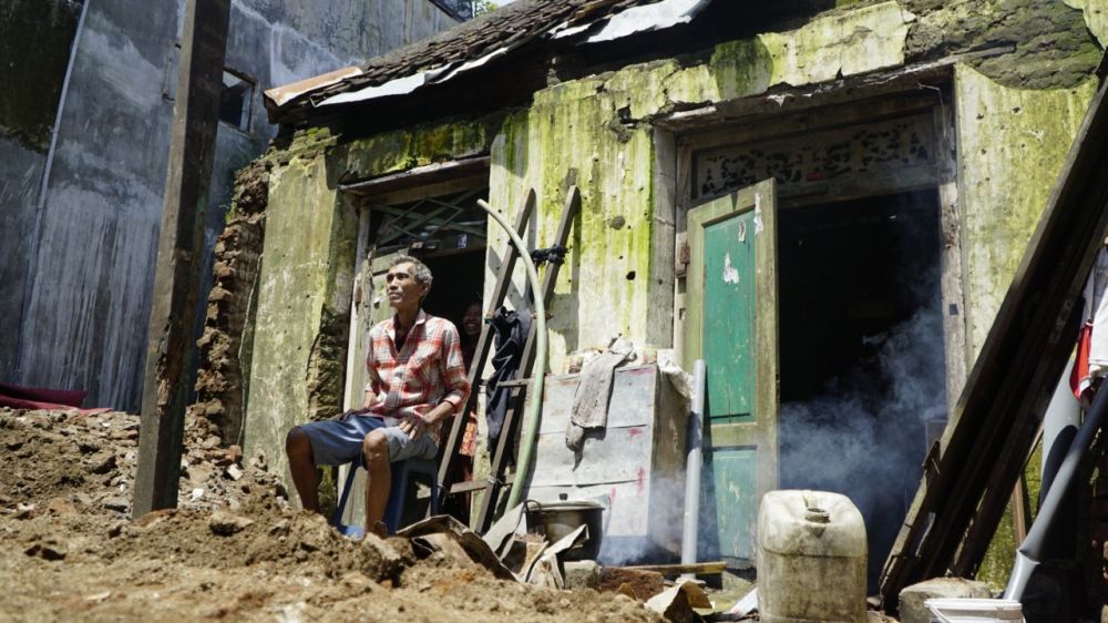 Supriyanto di depan rumahnya yang ambruk