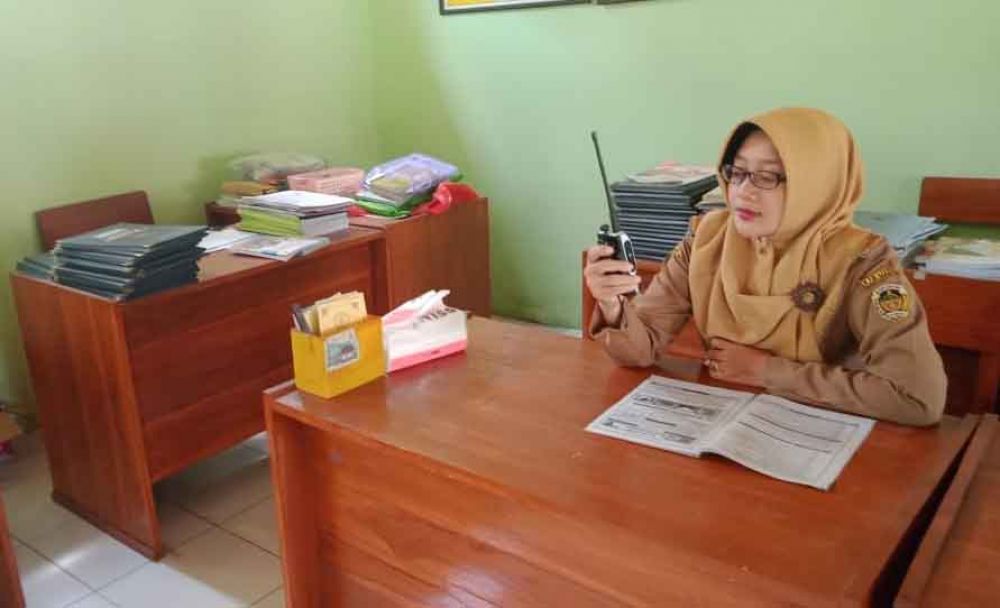 Guru kelas VI mengajarkan pelajaran menggunakan HT kepada muridnya