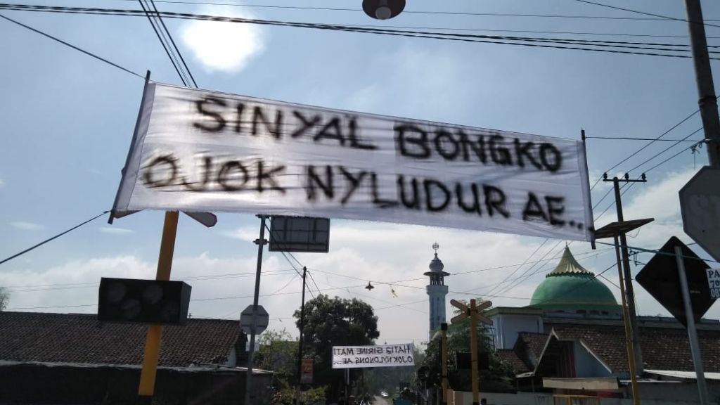 Spanduk 'pedes' yang dipasang warga di atas perlintasan kereta api