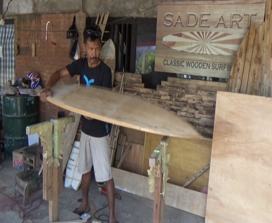 Wiet I Dewa sedang memproses papan surfing dari bahan kayu.