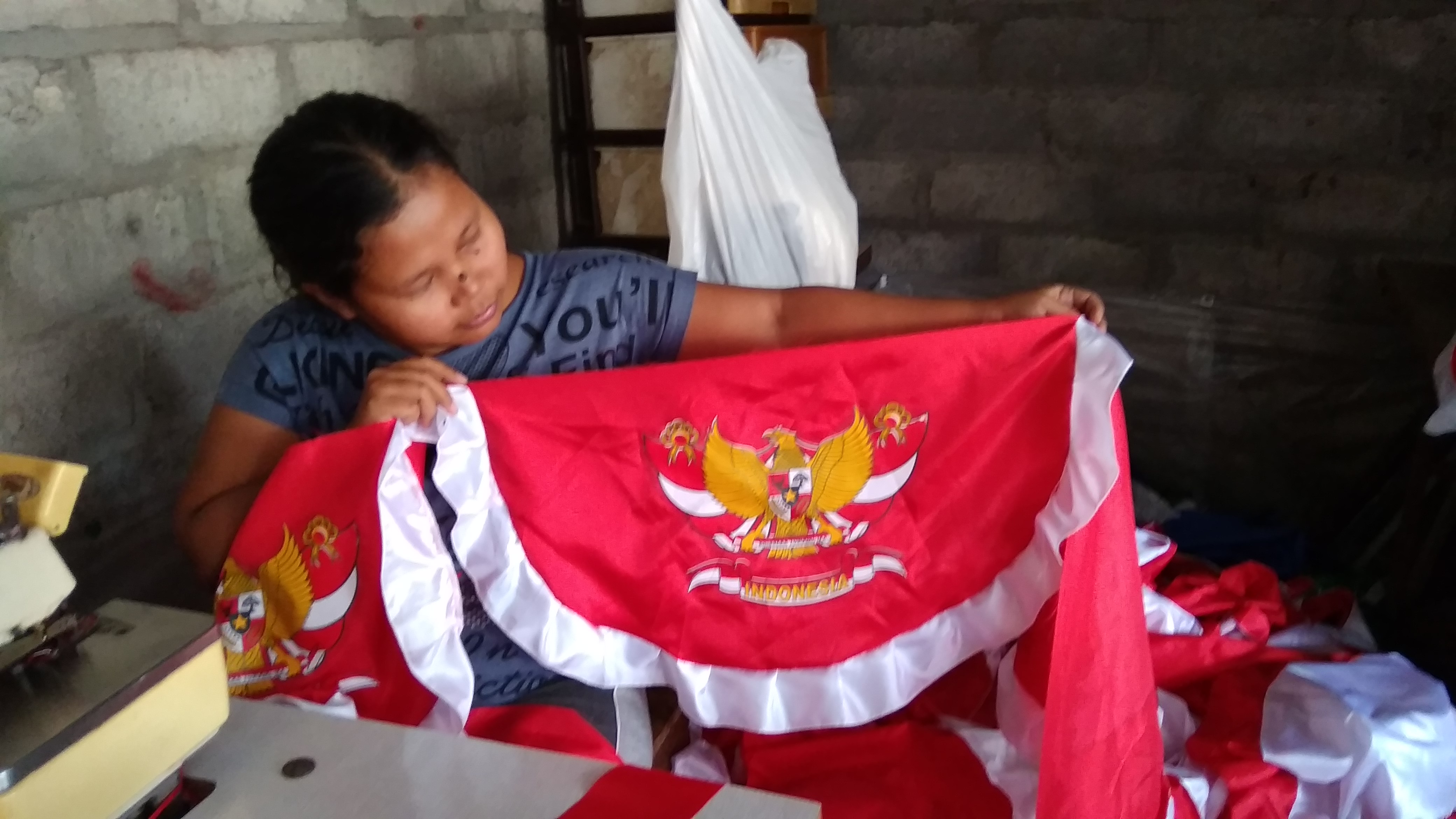 Penjahit tengah menyelesaikan pesanan bendera dan umbul-umbul
