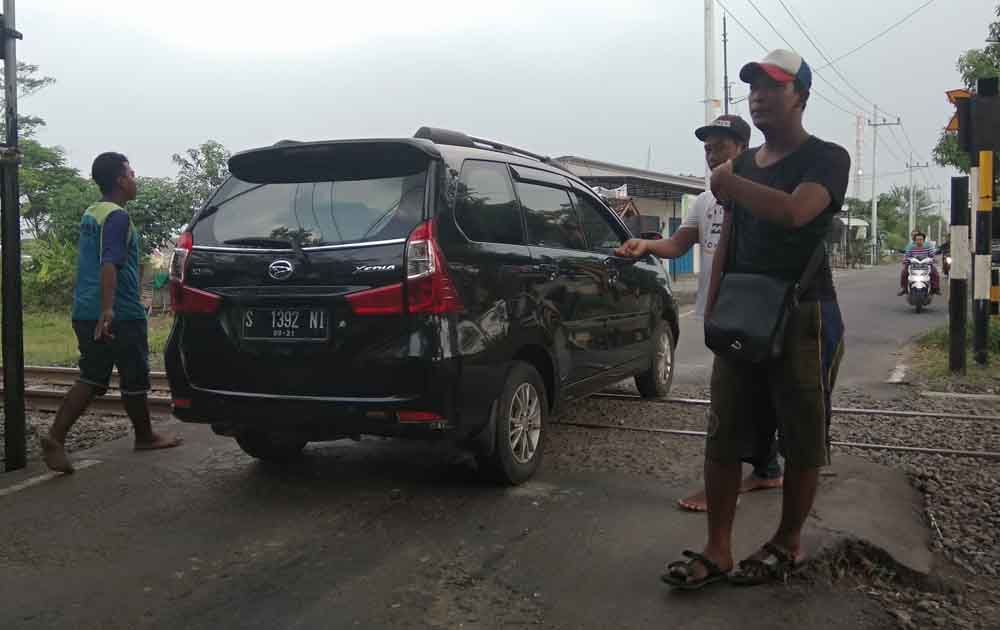 Muhammad Ridwan mengatur lalu lintas di rel tanpa palang pintu di Mojokerto