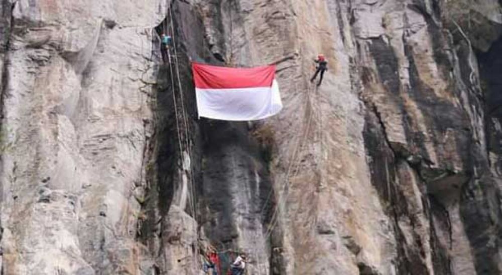 Bendera Merah Putih berukuran besar dikibarkan di tebing air terjun Kalipedati