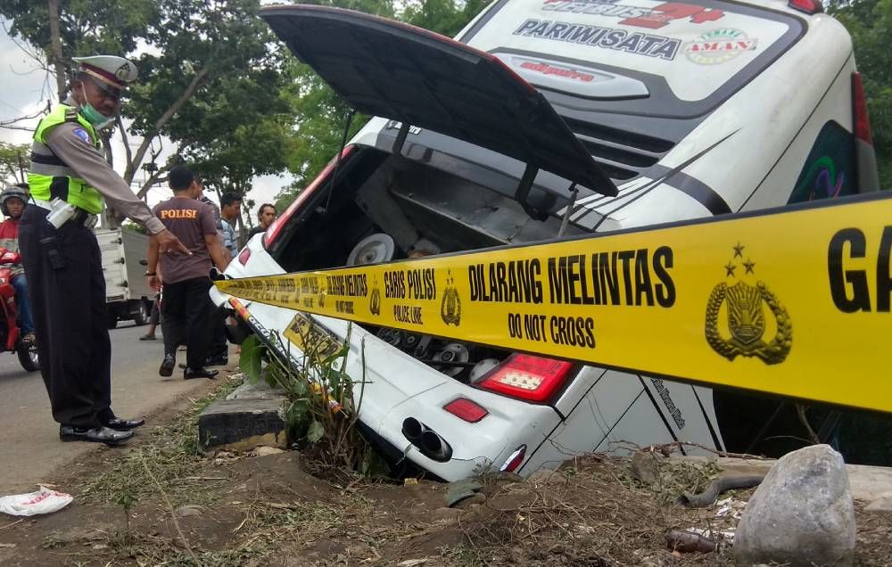 Pemasangan garis polisi di lokasi bus yang mengalami kecelakaan di Blitar