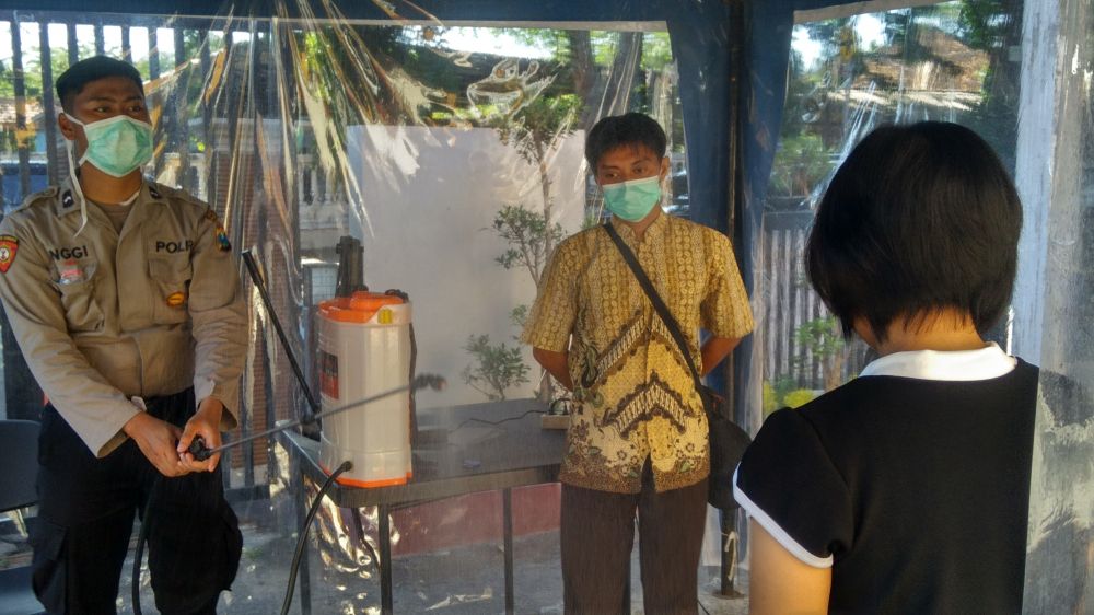 Polisi menyemprot disinfektan bagi warga yang datang ke Mapolres Probolinggo Kota