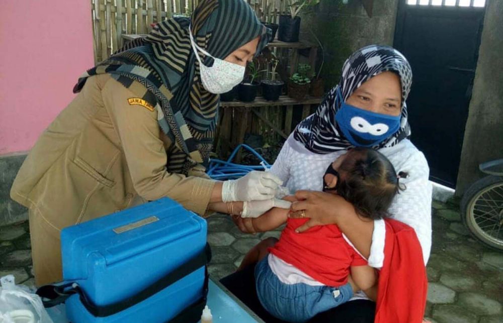 Salah satu petugas puskesmas di Banyuwangi mendatangi rumah warga untuk melakukan imunisasi balita