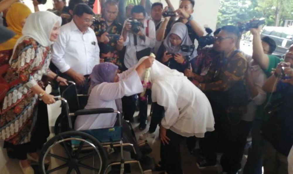Penyandang difabel perempuan mengalungkan bunga kepada Khofifah di Bandara Juanda