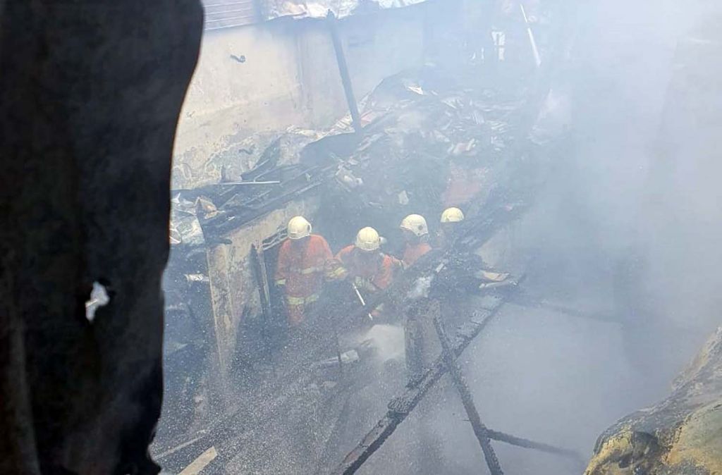 Petugas berusaha memadamkan api yang membakar tiga rumah semi permanen di Surabaya