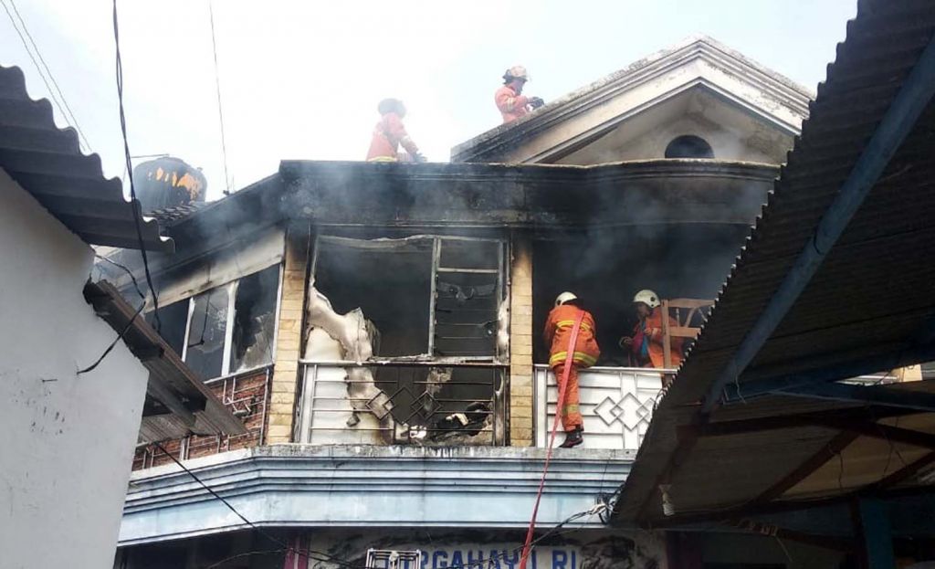Petugas pemadam kebakaran berusaha memadamkan api yang membakar lantai dua rumah di Surabaya