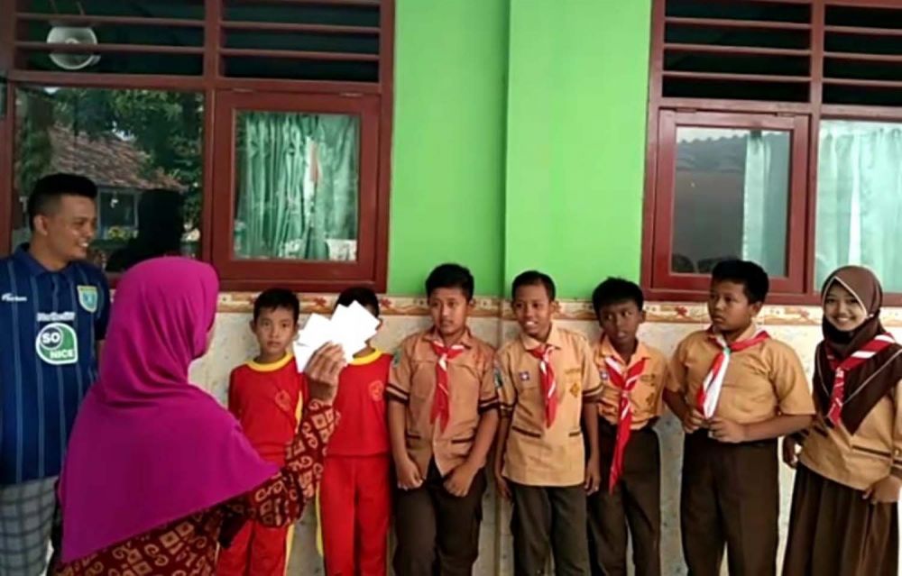 Taufik (kiri) memberikan santunan kepada seorang guru untuk diberikan kepada 7 anak yatim di SDN Puter 1, Kembangbahu, Lamongan
