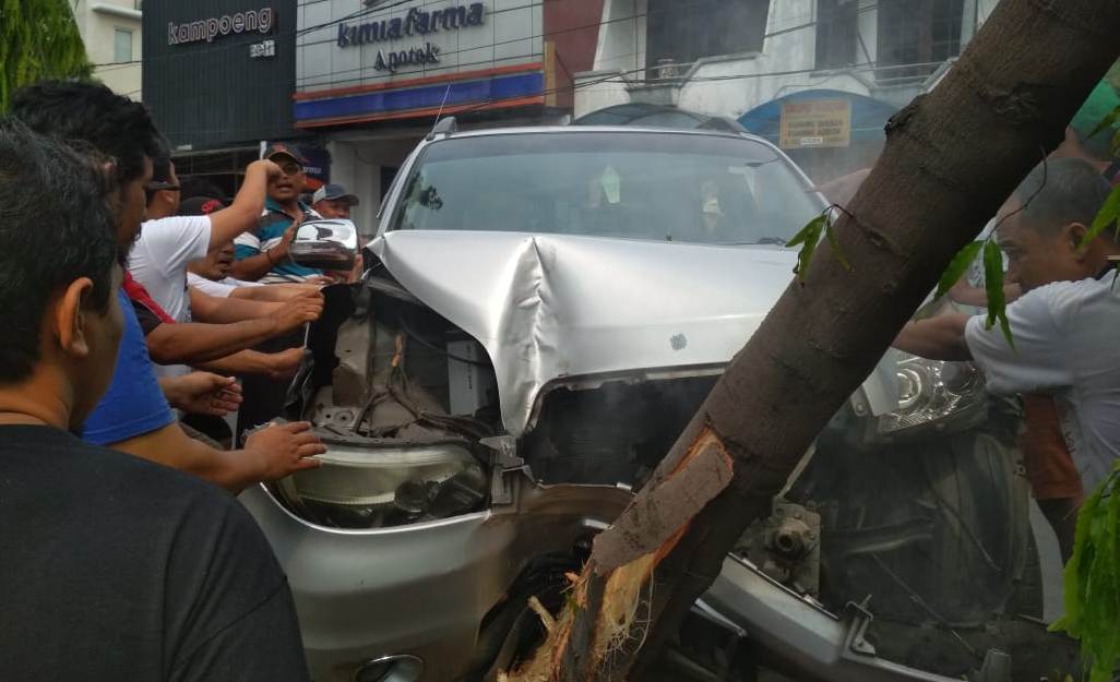 Warga membantu mengevakusi mobil Toyota Rush yang menghantam pohon