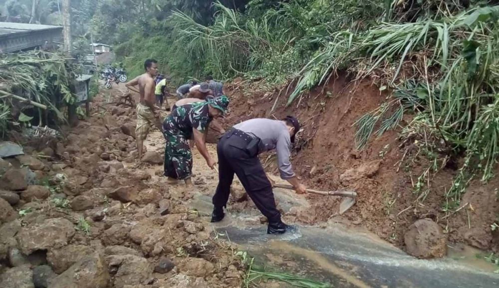 Tim BPBD, TNI dan polisi serta warga membersihkan material longsor yang menutup jalan desa di Kediri