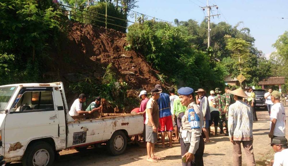 Petugas dan warga membersihkan material longsoran yang menutup jalan menuju Wisata Telaga Sarangan, Magetan
