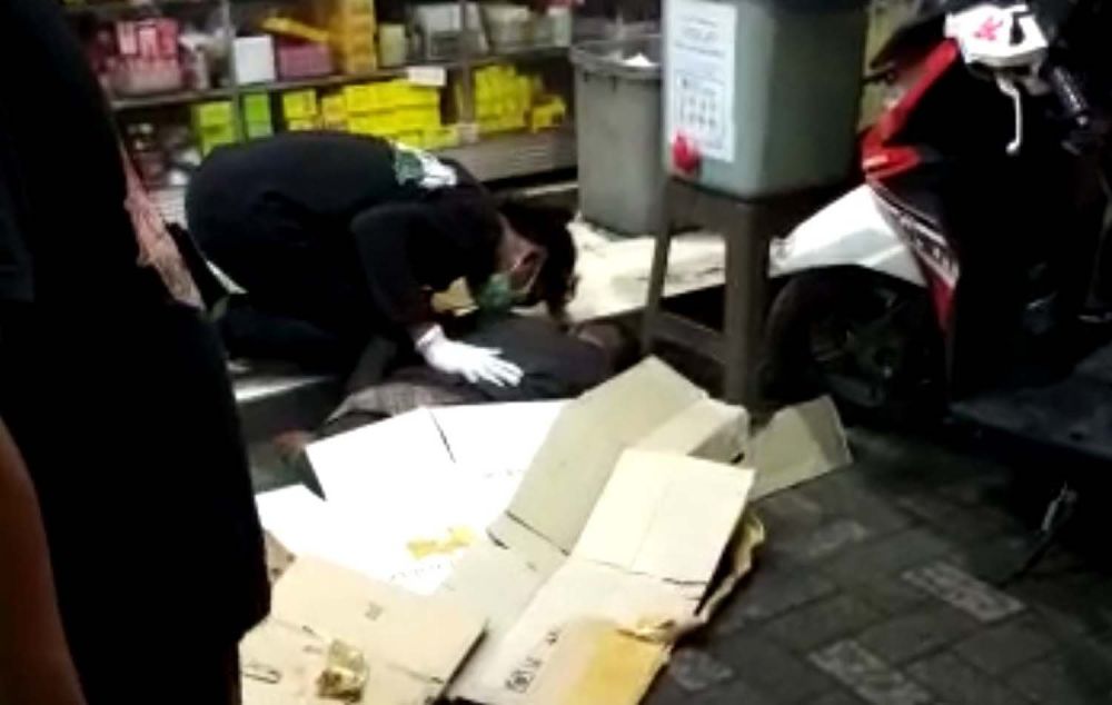 Seorang pemuda melihat jasad ayahnya yang meninggal dunia mendadak di depan sebuah apotek di Krian, Sidoarjo