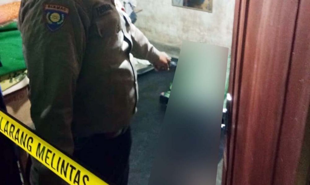 Polisi memasang garis polisi di lokasi tewasnya juru parkir dengan wajah penuh darah di Jombang