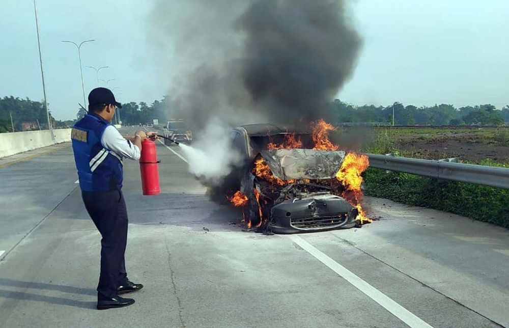 Petugas berusaha memadamkan mobil Mitsubishi Mirage yang terbakar di Tol Pandaan-Malang