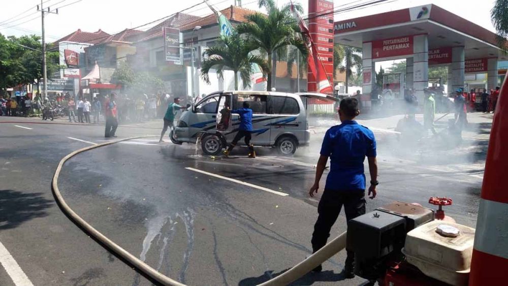 Petugas pemadam kebakaran berusaha memadamkan api yang keluar dari mobil Daihatsu Zebra di Magetan