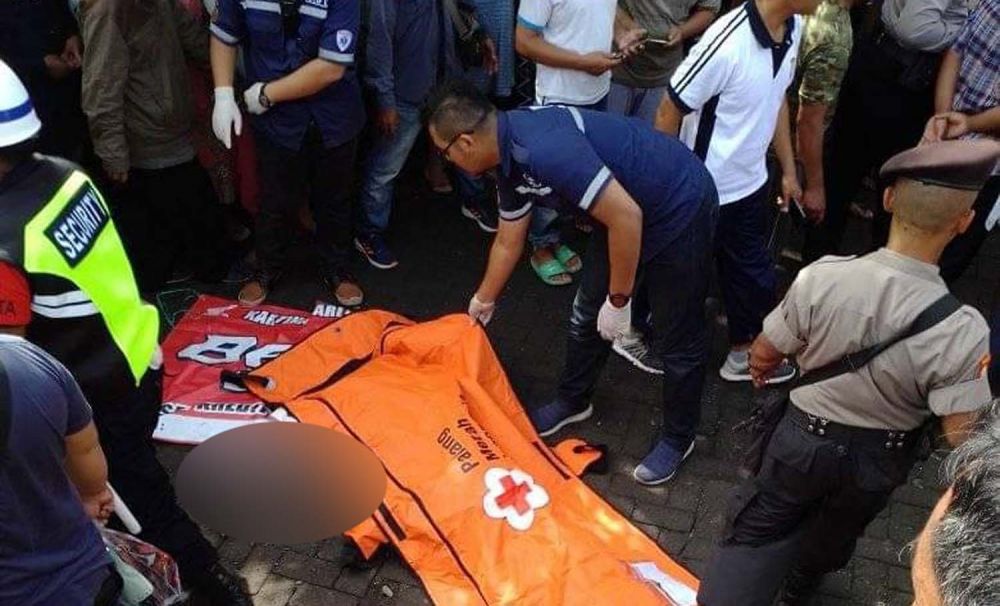 Petugas mengevakuasi salah satu jasad korban kecelakaan motor tersambar kereta api di Kota Malang