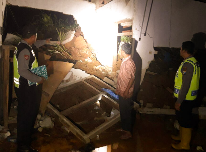 Petugas Kepolisian melihat kondisi rumah yang diterjang longsor.