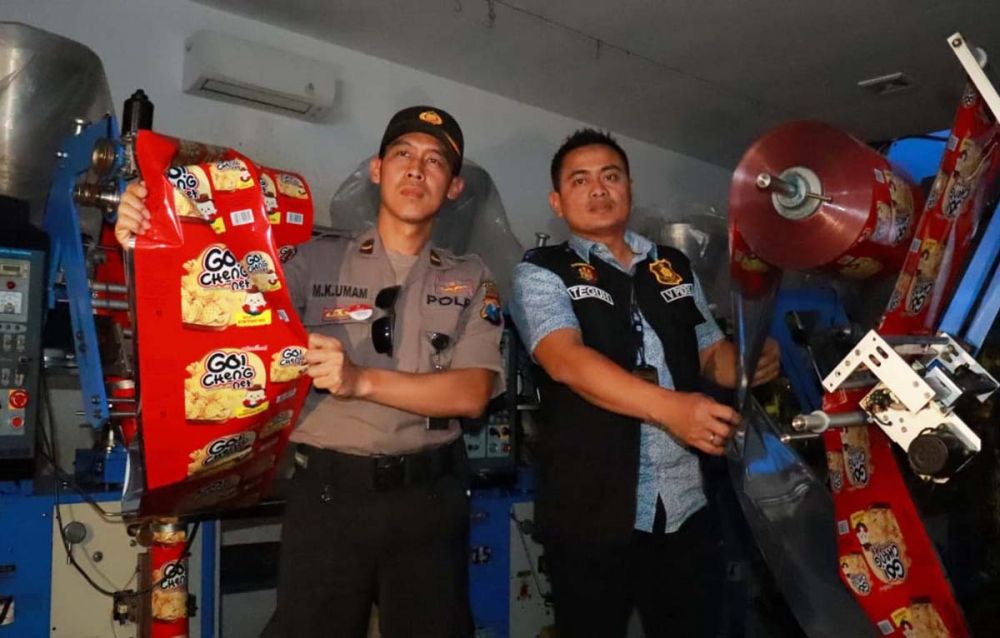 Kanit Pidek Polrestabes Surabaya AKP Teguh Setiawan (kanan) menunjukkan makanan ringan tanpa izin edar yang diproduksi PT USJ