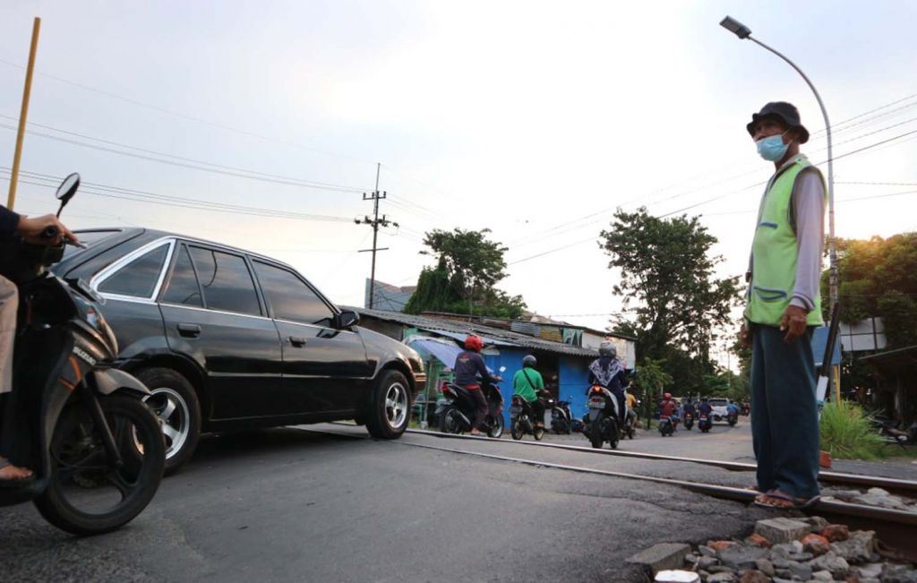 Kesi, saat berjaga di rel kereta api tanpa palang pintu di Surabaya (Foto-foto: Fajar Mujianto/jatimnow.com)