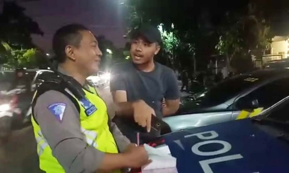 Aipda Abdul Malik Aziz, anggota Unit Lantas Polsek Genteng tetap tersenyum saat menghadapi pengemudi mobil yang tidak bersedia ditilang di Jalan Slamet atau sebelah Grand City Mall, Surabaya