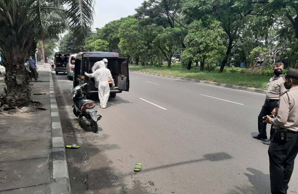 Petugas berpakaian APD mengevakuasi jenazah pengendara motor di Jalan Raya Margomulyo, Surabaya