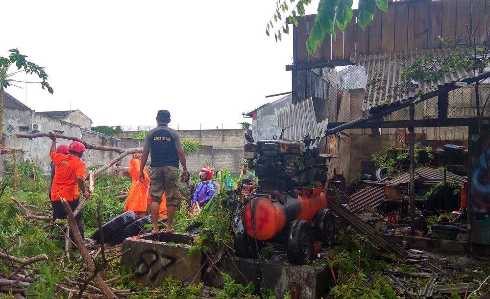 Petugas membersihkan dahan pohon tumbang timpa bengkel akibat hujan angin di Kota Blitar