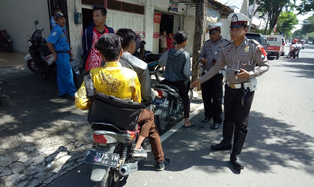 Anggota Polisi Lalu Lintas Polsek Rogojampi saat meberhentikan siswa yang tidak mengenakan helm.

 