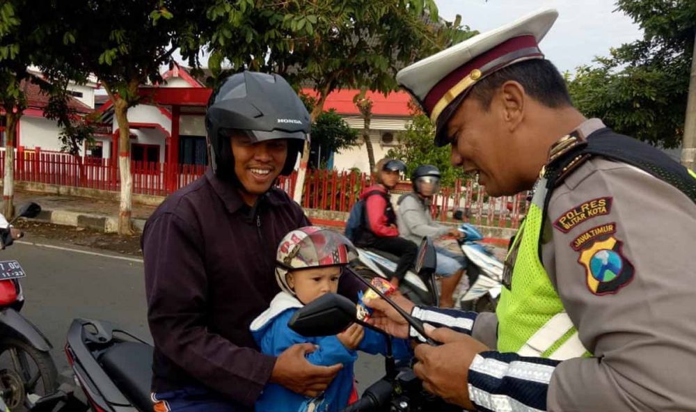Kanit Dikyasa, Satlantas Polres Blitar Kota, Ipda Samsul Anwar memberikan hadiah cokelat kepada anak-anak