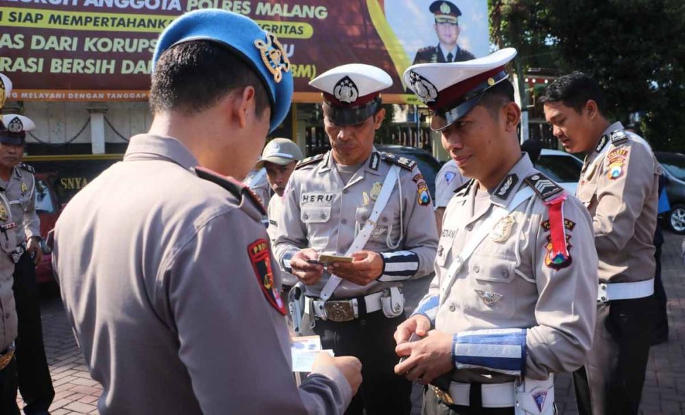 Anggota Propam Polres Malang memeriksa kelangkapan identitas anggota polisi usai apel pasukan
