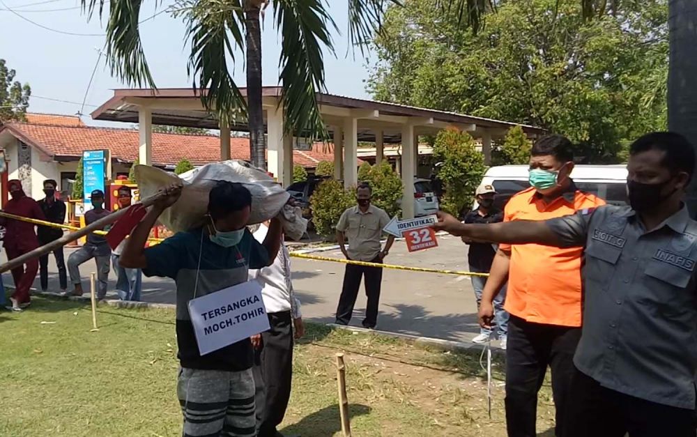 Tersangka Tohir memperagakan pembuangan mayat Raisa dalam rekonstruksi di Mapolres Pasuruan