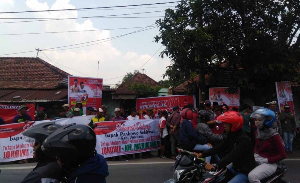 Relawan Jokowi menyambut kedatangan Prabowo dengan membentangkan spanduk di Losari, Ploso, Jombang, Minggu (24/02/2019)