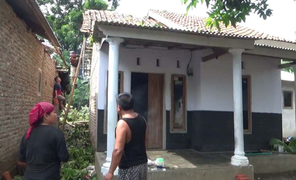 Warga di Pasuruan memperbaiki rumahnya yang rusak akibat hujan angin