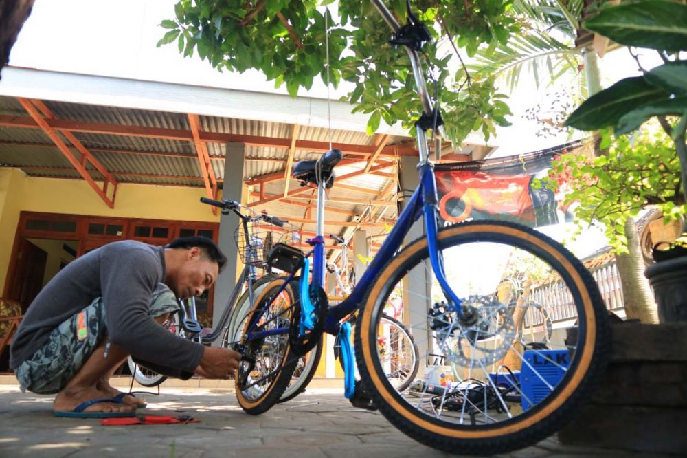 Lukman membenahi sepeda minion di bengkelnya di Ponorogo