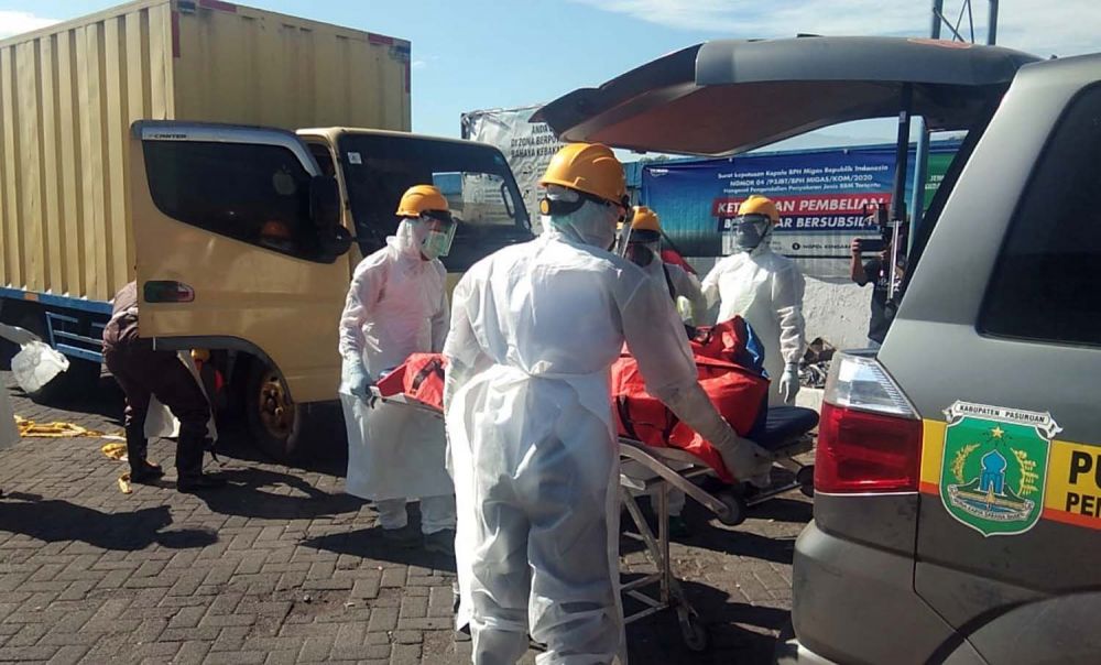 Petugas berpakaian APD mengevakuasi jenazah sopir truk di Pasuruan