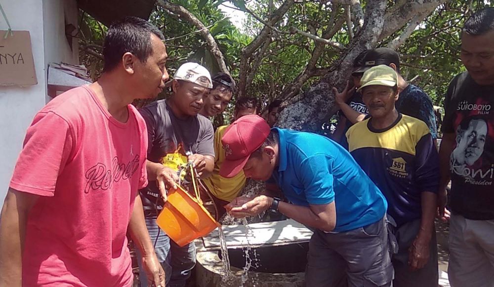 Warga mengantri membasuh muka dan mengambil air hangat dari sumur ajaib di Makam Watutulis, Sidoarjo