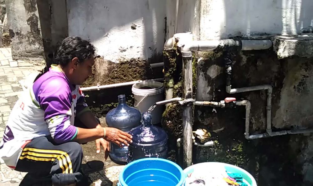 Salah satu warga mengambil air bersih yang keluar dari Sumur Mumbul Pasuruan