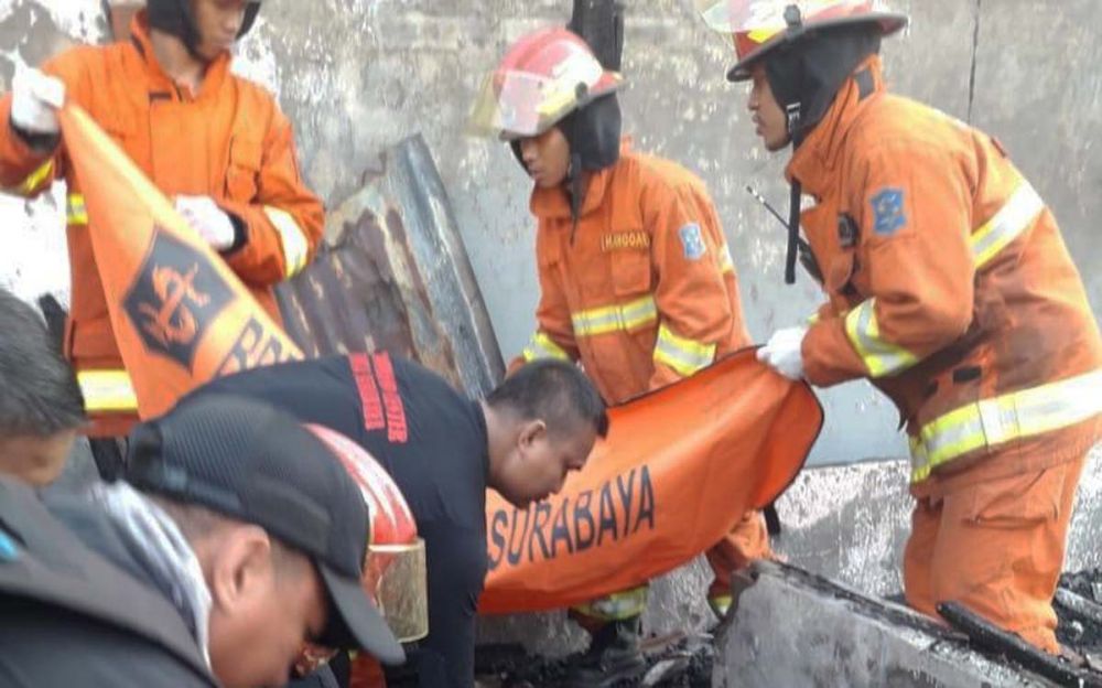 Petugas mengevakuasi jasad korban dari rumahnya yang terbakar di Kenjeran, Surabaya