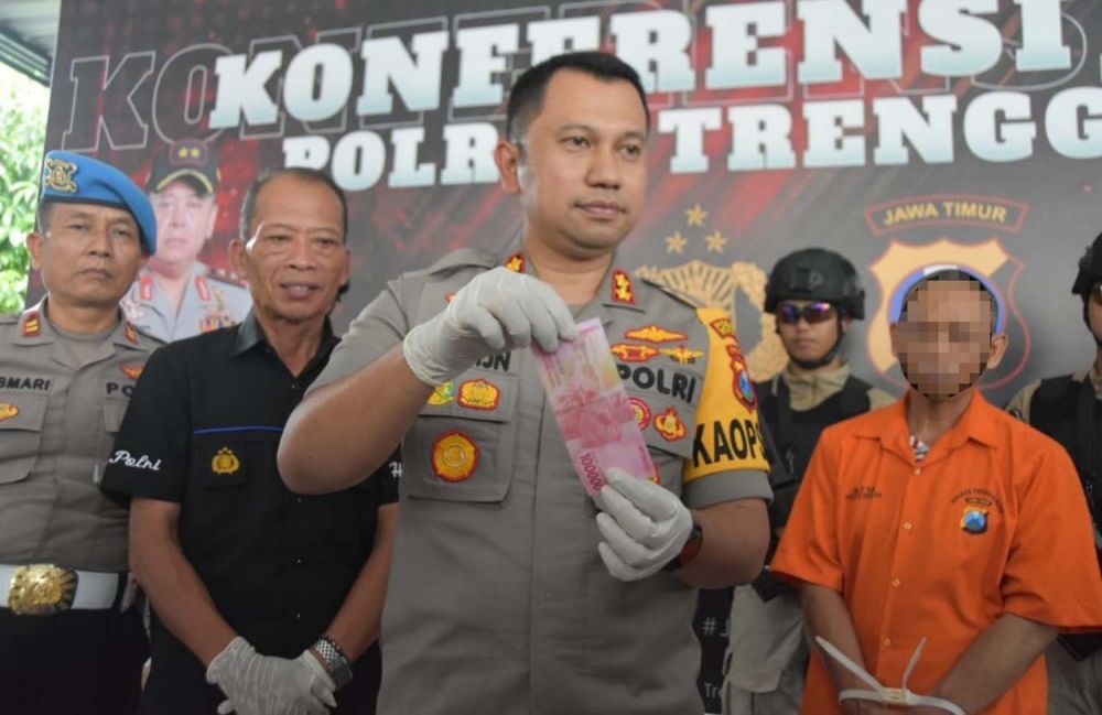 Kapolres Trenggalek AKBP Jean Calvijn Simanjuntak menunjukkan salah satu uang palsu yang disita dari dua tersangka