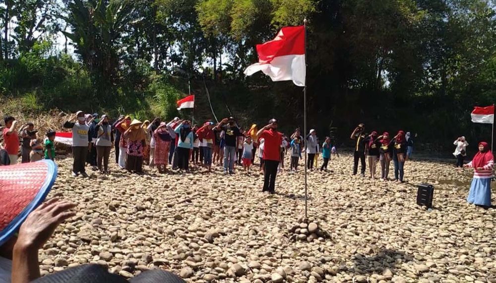 Warga Desa Sukosari, Kecamatan Babadan, Kabupaten Ponorogo mengikuti upacara HUT ke-75 RI di tepi Sungai Dayang