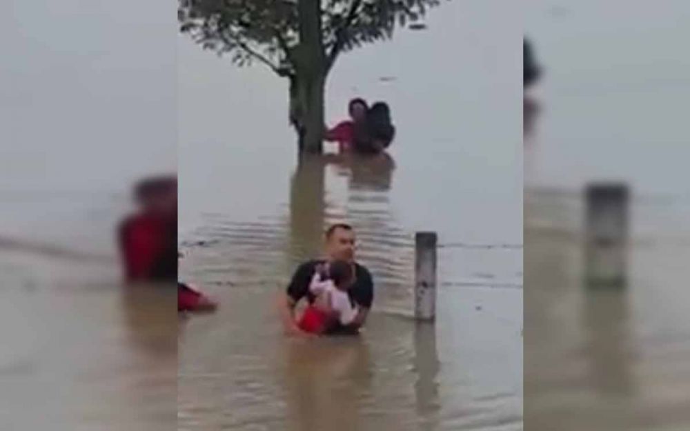 Aksi Aiptu Sujadi saat menolong keluarga korban banjir di tepi Tol Ngawi-Kertosono